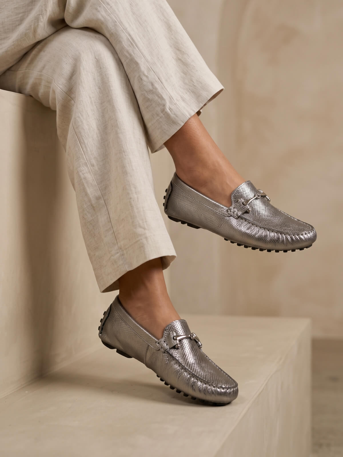 Drivers Enchazados Amalfi color plomo en cuero para mujer, con acabado texturizado y aplique metálico elegante.