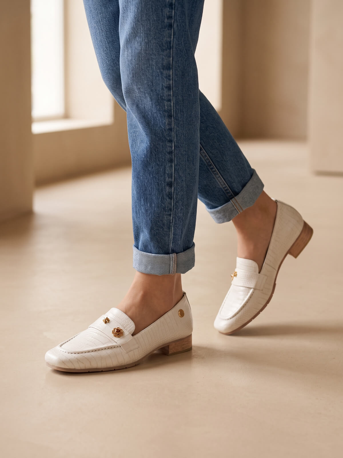 Mocasines color hueso para mujer con detalle de antifaz y apliques decorativos, ideales para looks casuales y elegantes.
